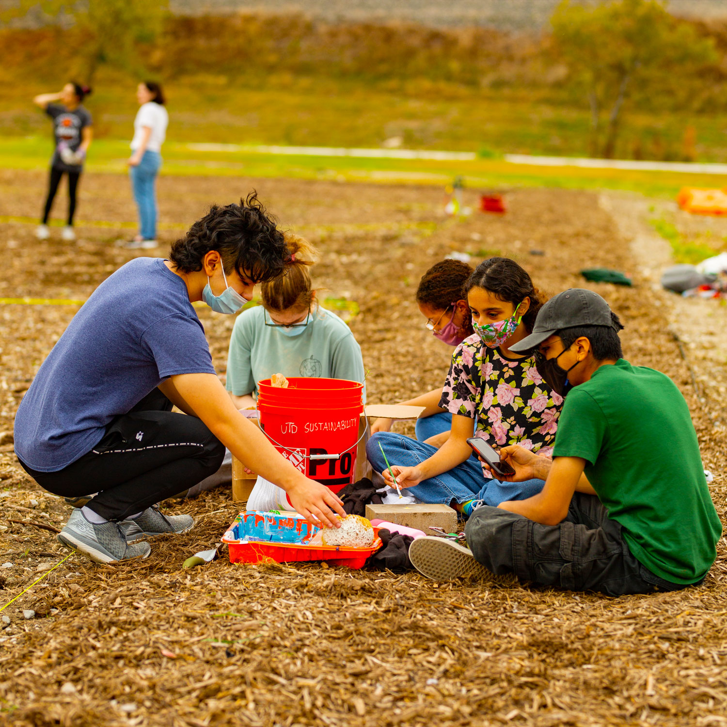 Students sitting in a circle around some gardening supplies.