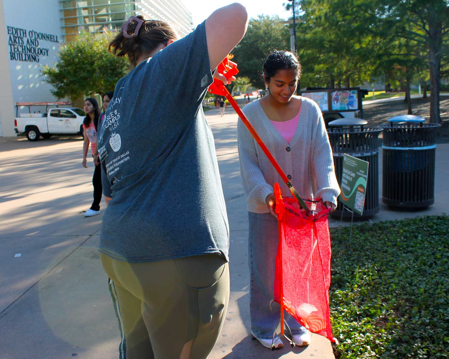 An Eco Rep and a student collect garbage on the UT Dallas campus.
