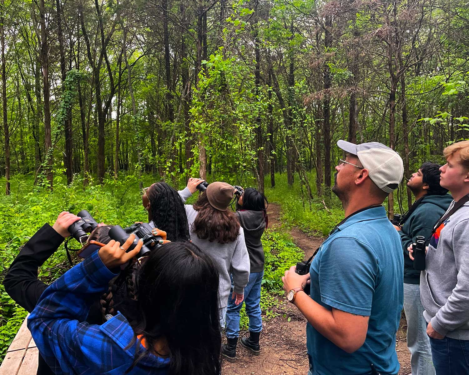 A group of student birdwatchers in a forrest.