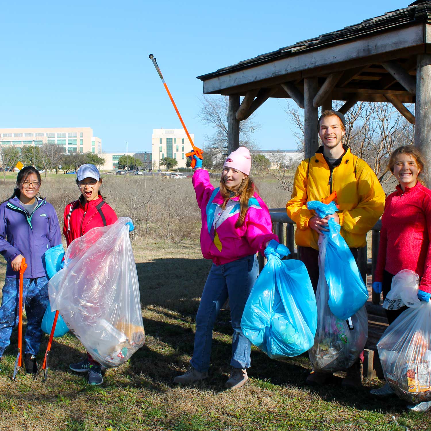 Five students with collecting trash and recyclables into bags.