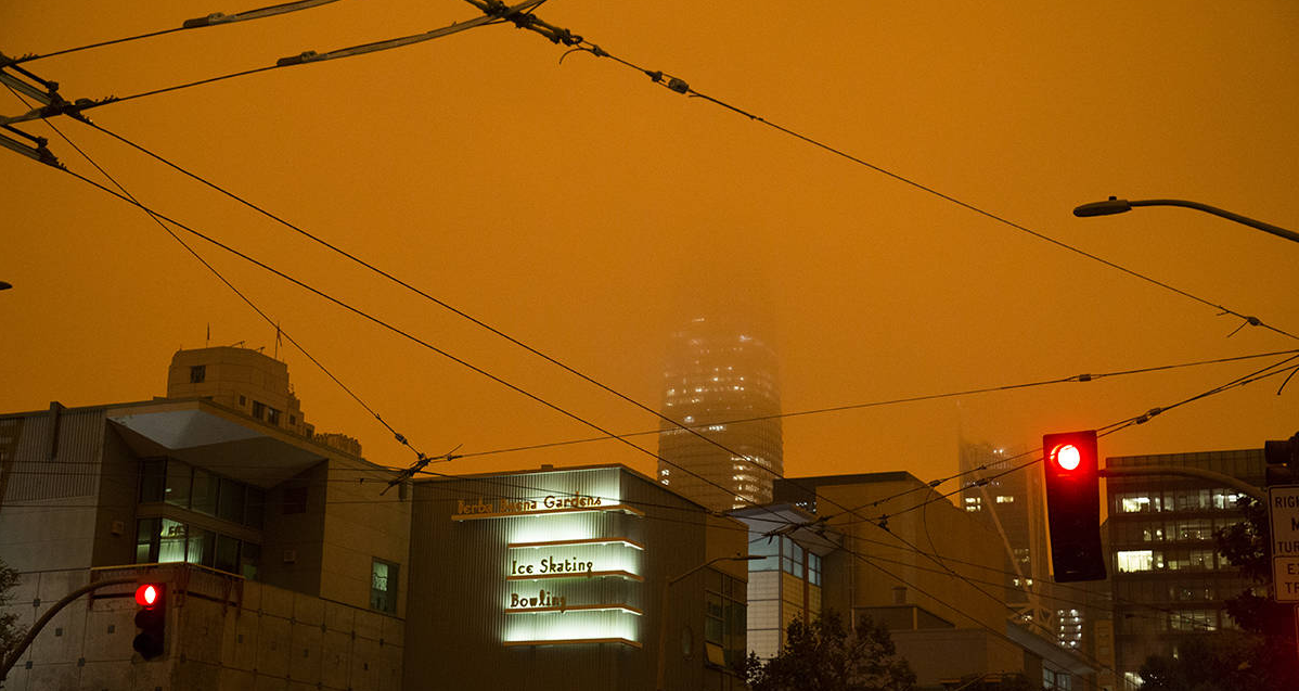 Buildings shrouded in a cloudy half-light, their tops disappearing into an orange sky.