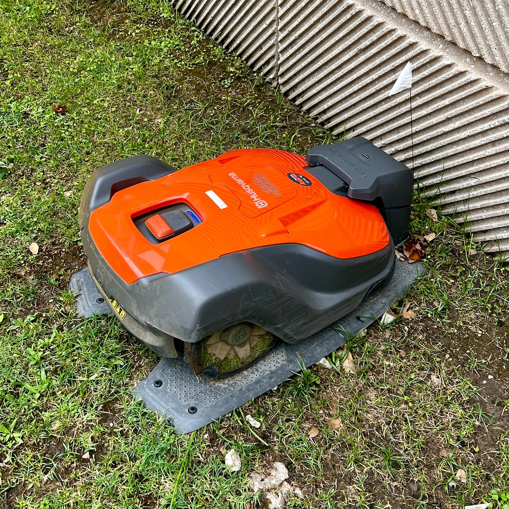 A squat orange and grey machine parked along a wall at a charging station.