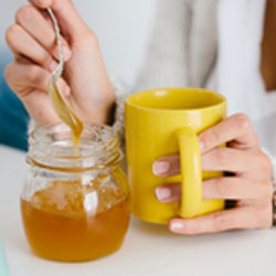 Fungi to the Rescue. A person spooning honey from a jar to a mug.