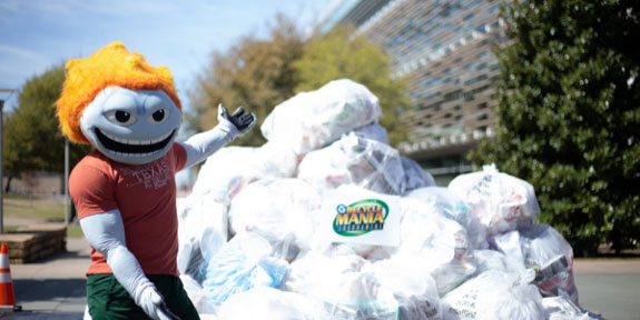 Get Ready for Campus Race to Zero Waste. University mascot Temoc in front of a pile of filled recycling bags.