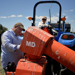 Right to Repair Movement Enters Congress. A farmer works on his tractor while a child looks on from the driver’s seat.