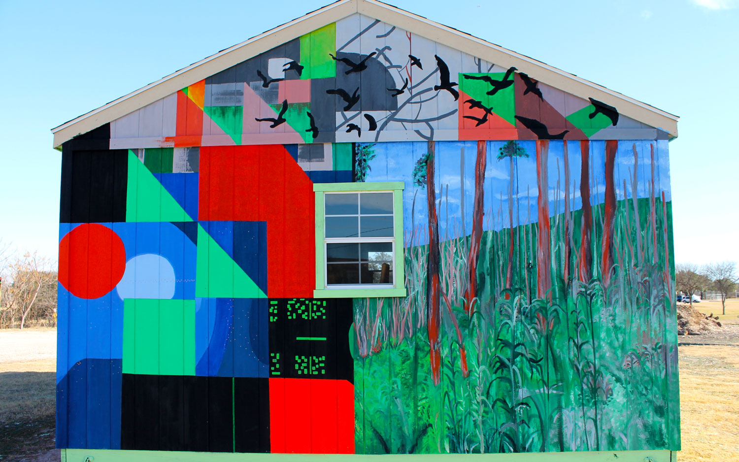 The side of a single-story gabled-roof building, painted with geometric shapes that get partially covered by a nature scene and birds.