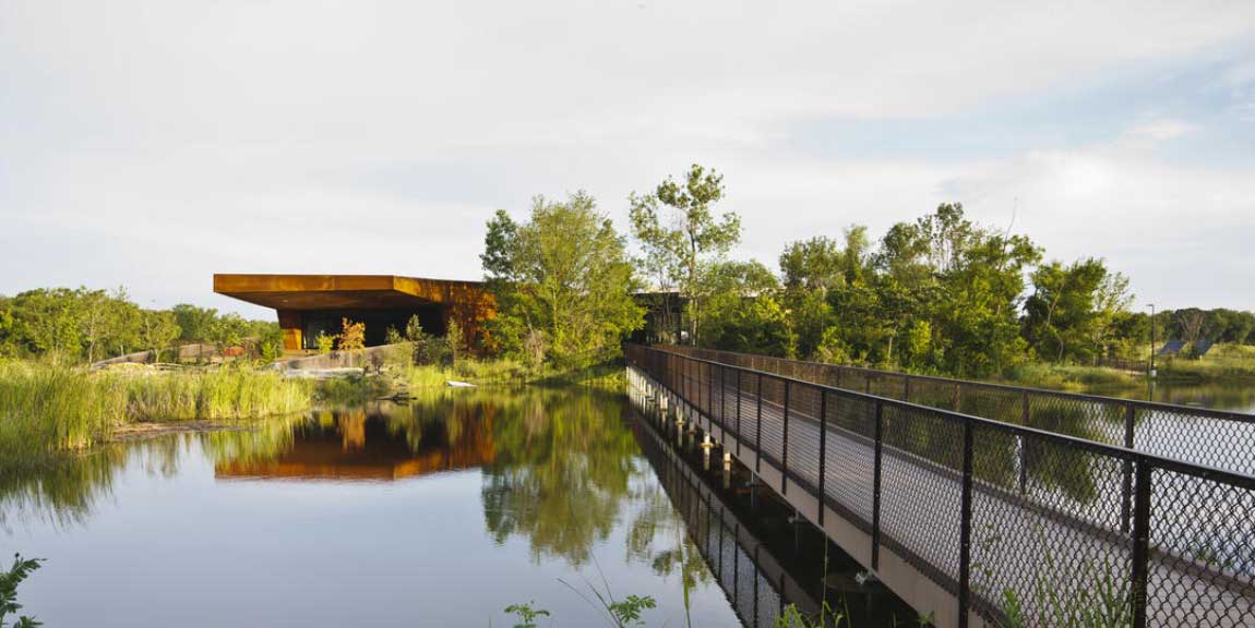 A walkway over water leading to the Trinity River Audubon Center.