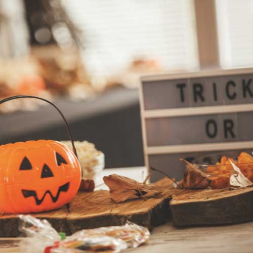 A tabletop bearing a plastic Jack-O-Lantern, other seasonal decorations, and candy.