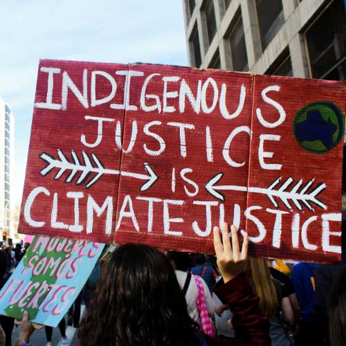 A sign held aloft at a rally, reading “Indigenous Justice is Climate Justice”.