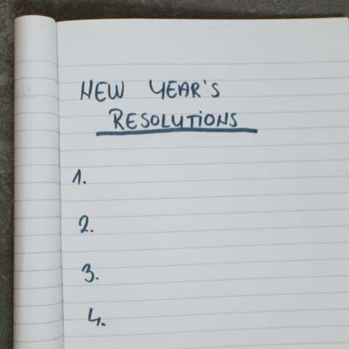 A notebook open to page where “New Year’s Resolutions” is written at the top, followed by an numbered list that is still empty.