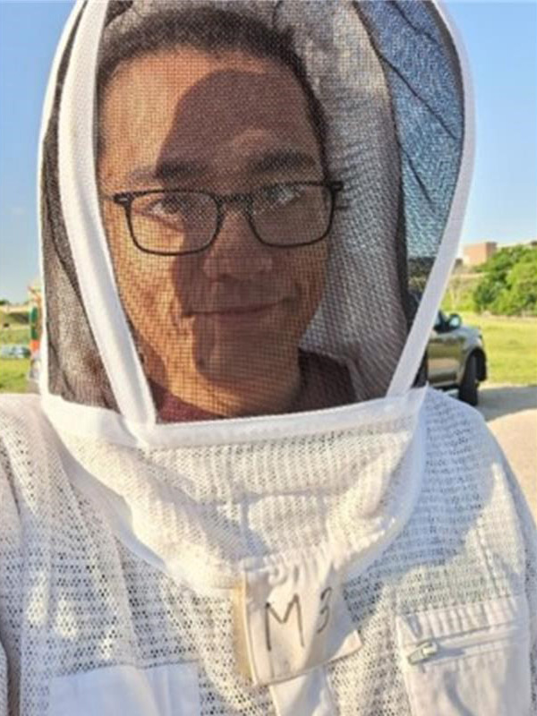 A man wearing protective beekeeper gear.