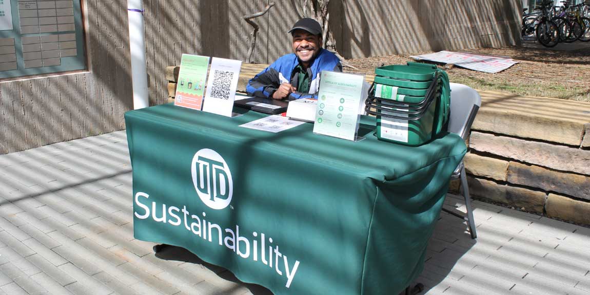 An Eco Rep sitting at an information table on the campus mall.