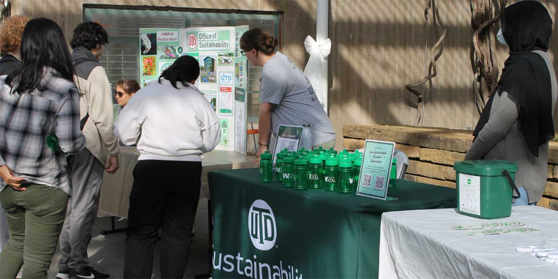 A trio of Eco Reps engaging with students at a table outdoors.