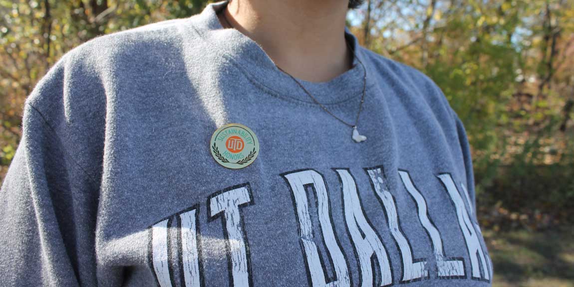 A close-up of a UTD Sustainability Honors badge pinned to a student’s UT Dallas sweatshirt.