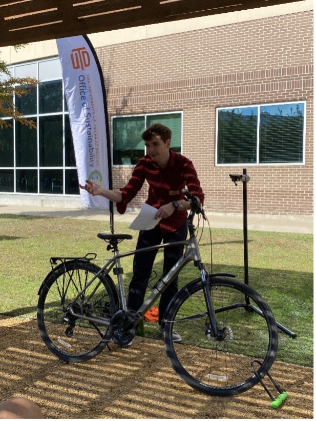 A student with a bike and a sign that reads “Bike Friendly University”