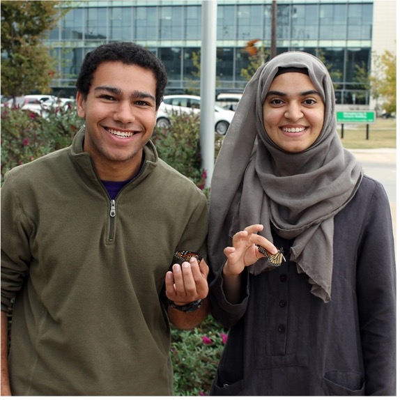 Two students holding butterflies in their hands.