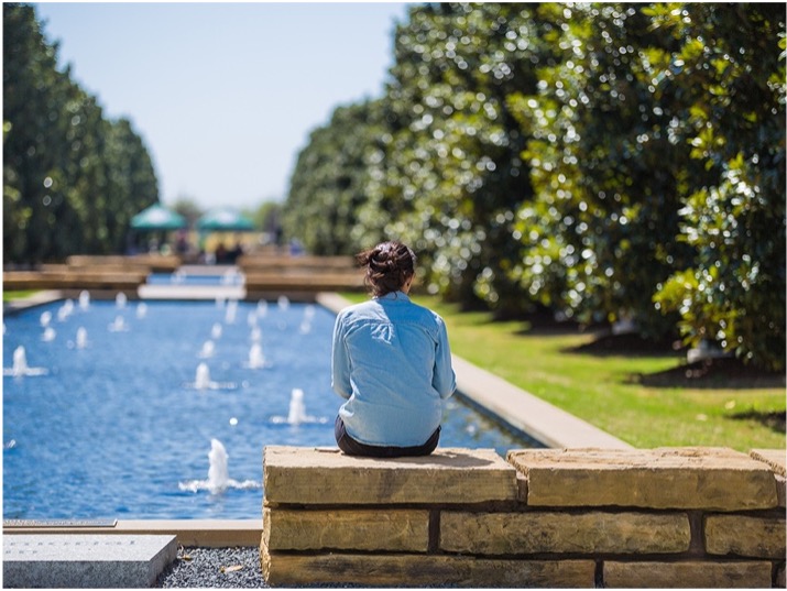A student sits next to a reflecting pool. A student sits next to a reflecting pool.