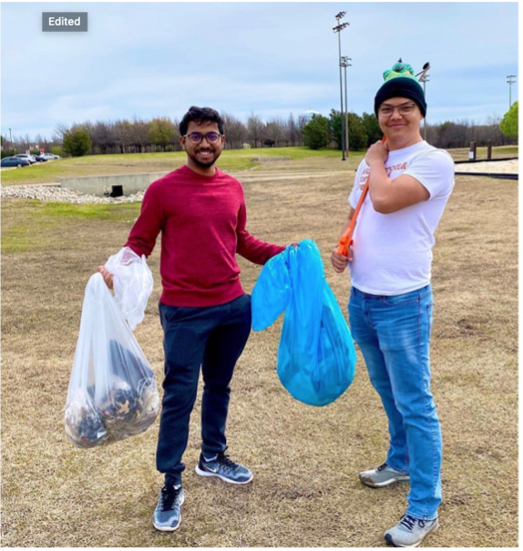 Two students hold up bags of trash and recyclables.