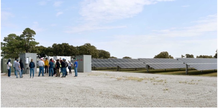 A group of students next to a solar energy farm.