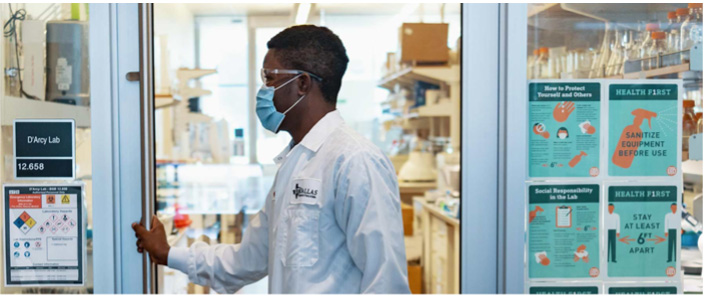 A researcher in safety gear prepares to enter a lab.