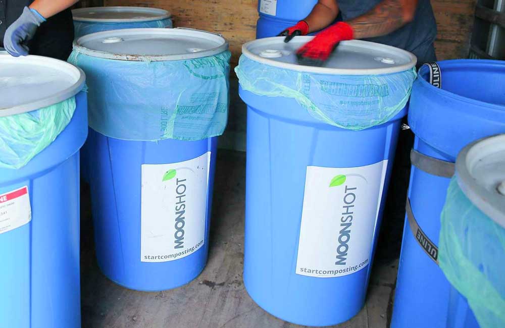 A large composting bin standing outside a building.