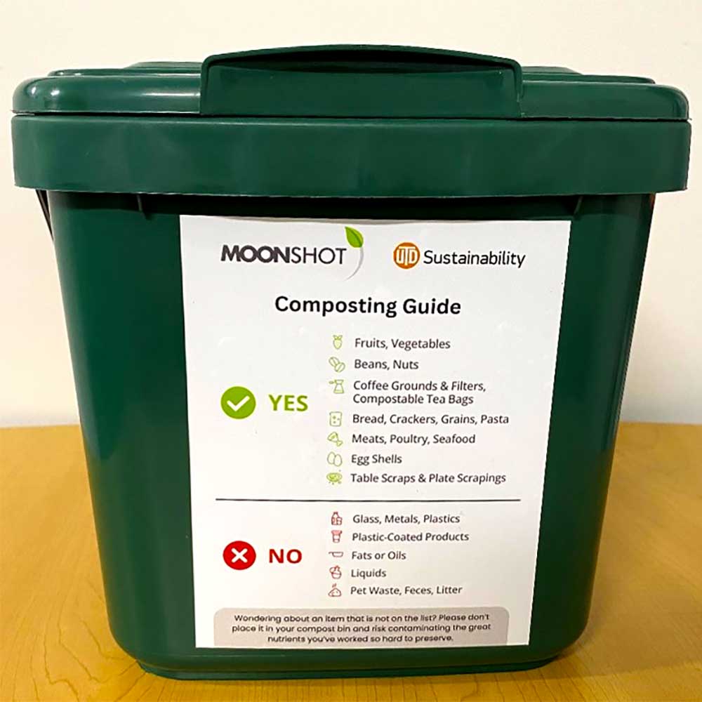 A small UT Dallas composting bin bearing a label with a composting guide.