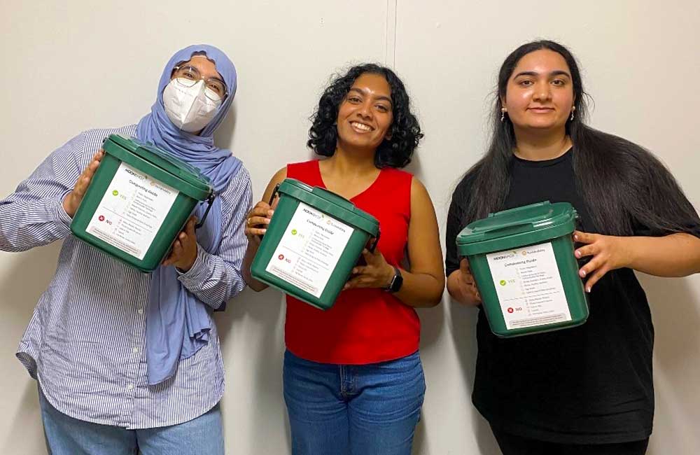 A trio of Eco Reps, each one holding a small composting bin.