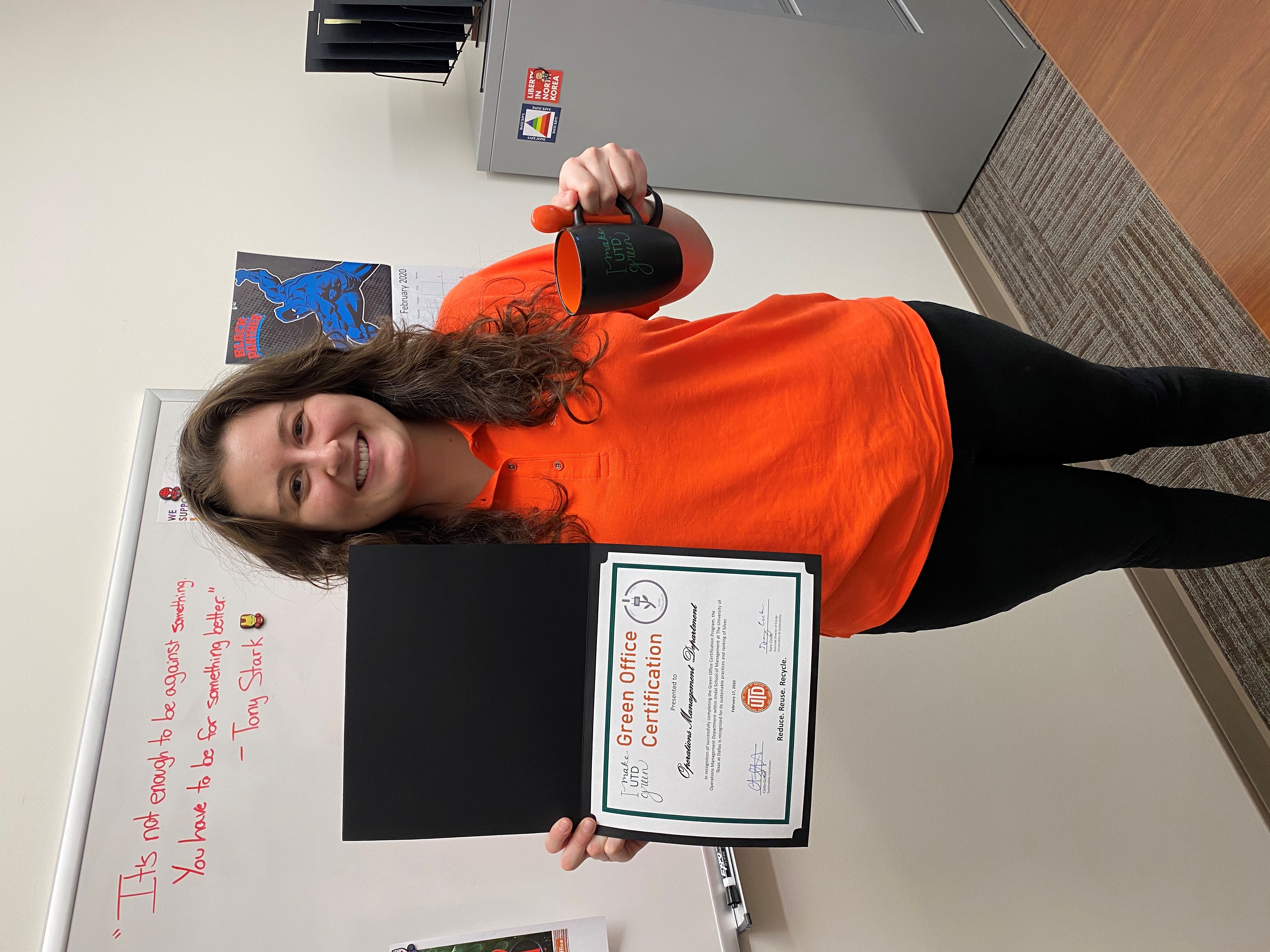 A Green Office participant holding up her certificate and mug.