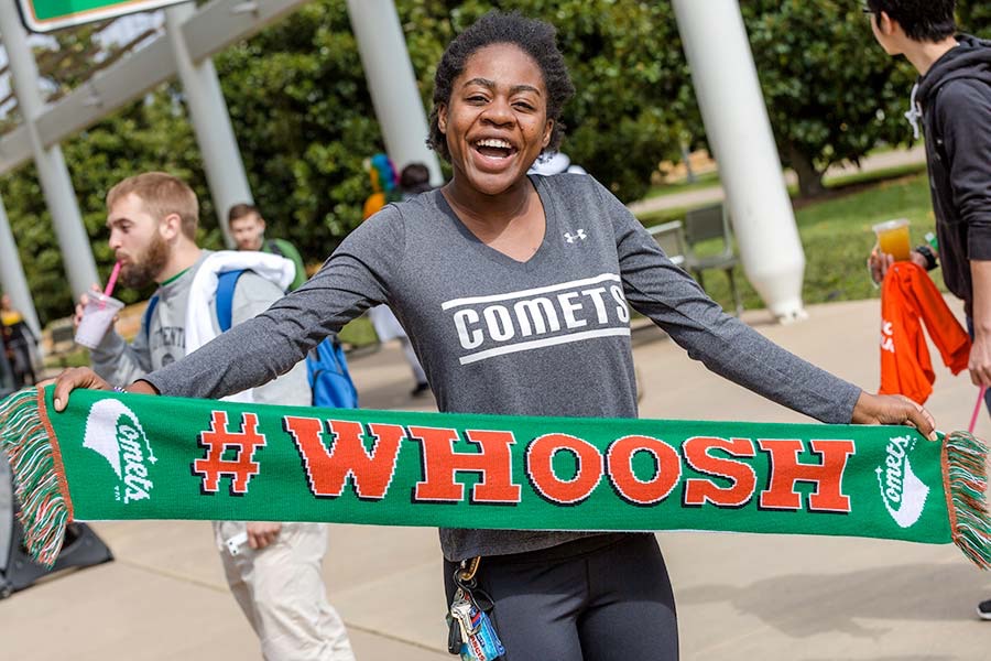 A student displaying a scarf the reads “Whoosh”.